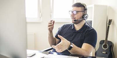 Male financial representative wearing a headset at a desk in front of a computer screen