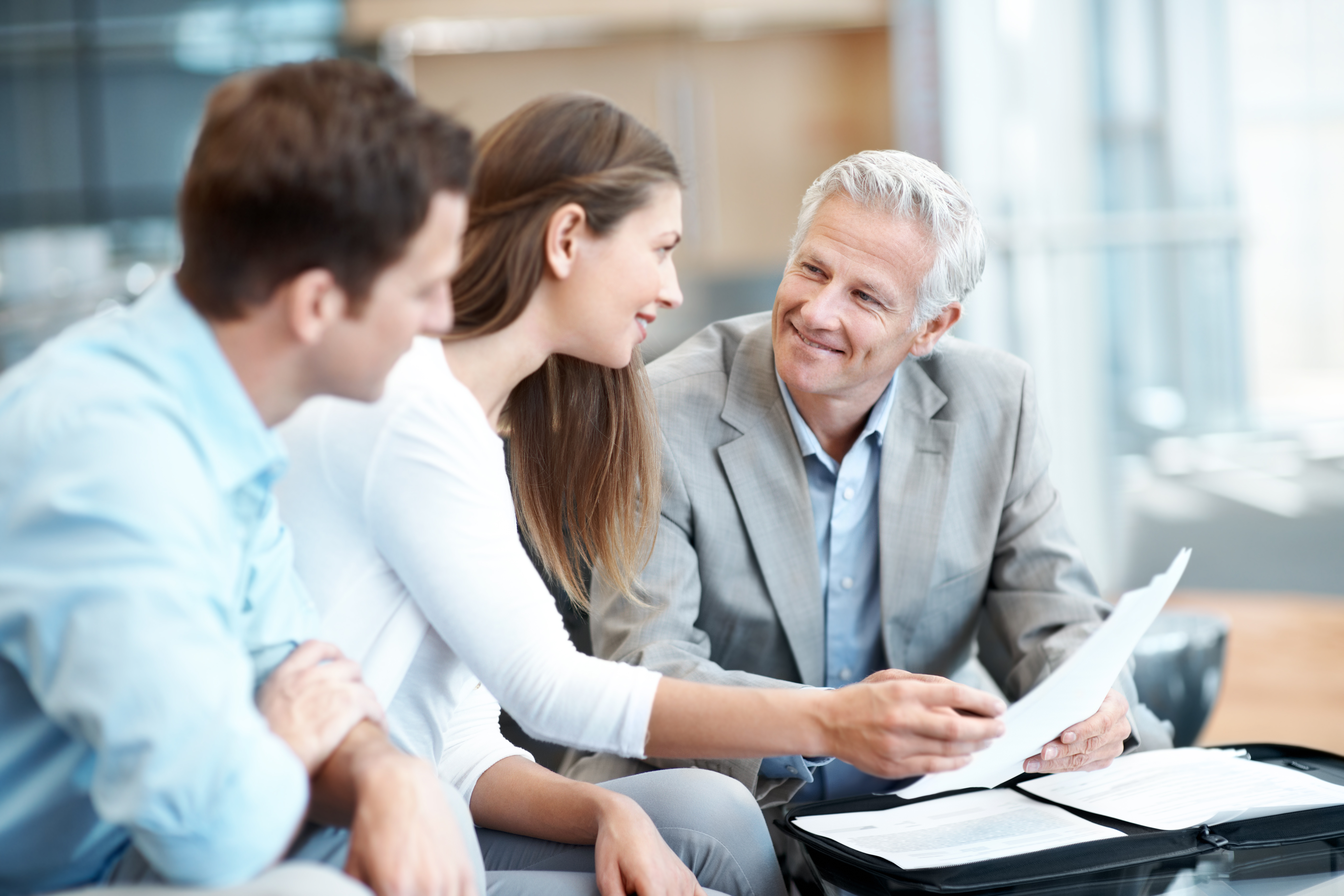 Male financial advisor smiles as he helps a young couple start their financial planning.