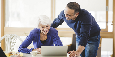 Adult son helping elderly mother with laptop