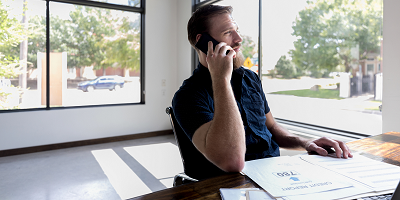 Man talking on phone looking at credit report on desk