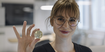 Woman with glasses holding a gold coin