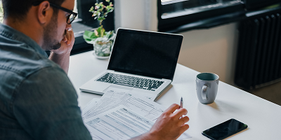 Man at desk with laptop filling out tax forms