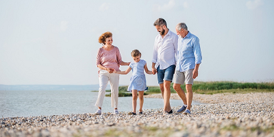 A multigenerational family walking together on the beach. 