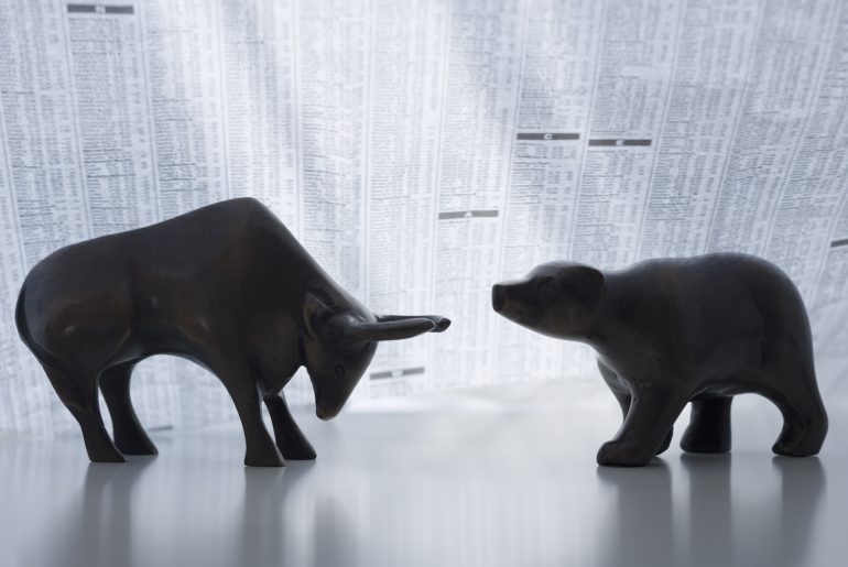 Bear and bull figurines with newspaper backdrop.