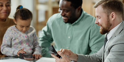 Male life insurance agent sitting at table with paperwork across from clients
