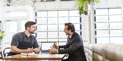 Restaurant owner and life insurance agent sitting at table and talking