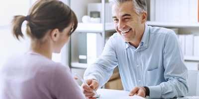 Middle aged woman smiling as she discusses her life insurance coverage options with her agent. 