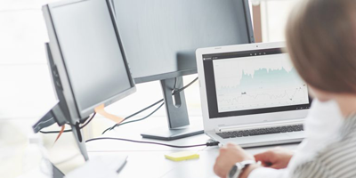 Female advisor reviewing graphs of product performance on her desktop computer. 