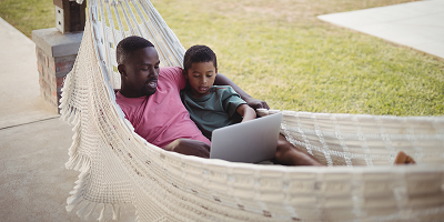 Dad and son in hammock using laptop