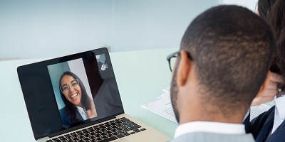 Man and woman using a laptop to talk to a female financial advisor on video
