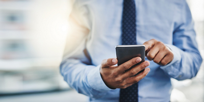 A business man in a tie looking at his smartphone.