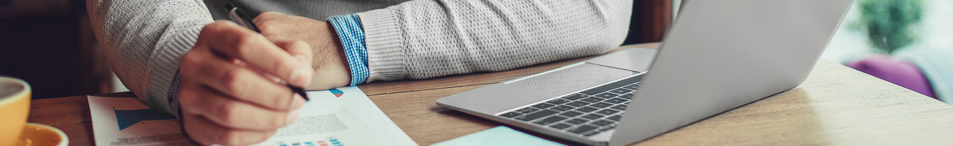 A young professional taking notes while attending a virtual seminar on their laptop.