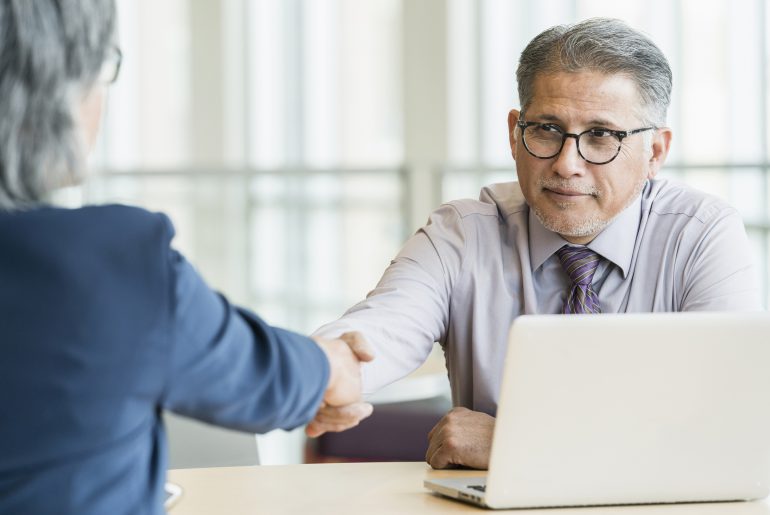 Male financial advisor shakes hand with female client.