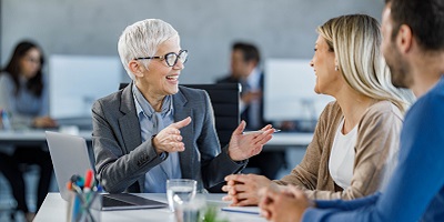 Female financial advisor smiles and laughs with a young couple